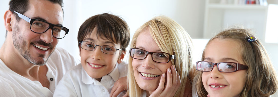 Family of four wearing glasses and smiling.