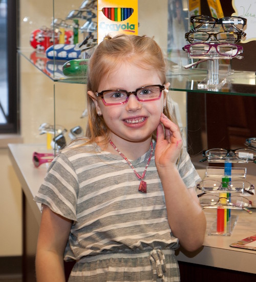 Little girl smiling wand posing while trying out her new glasses at Eye & Vision Clinics, S.C.